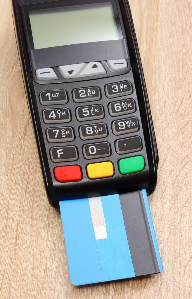 Payment terminal with credit card on desk, paying for shopping concept